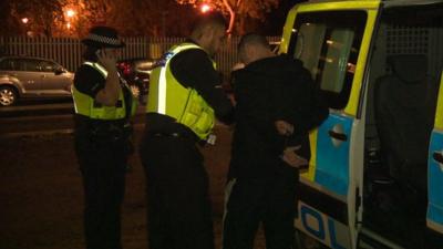 Two police officers searching a young man