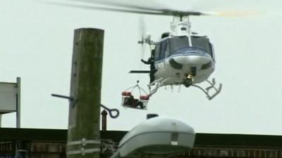 A helicopter winches someone on board