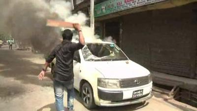 Protester striking car with baton