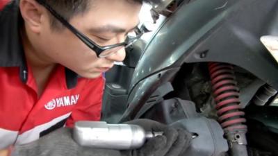 Man in Taiwan working on a motorbike