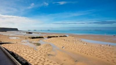 Volunteers creating figures in the sand on Arromanches beach