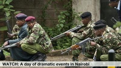 Armed police from the General Service Unit take cover behind a wall during a bout of gunfire, outside the Westgate Mall in Nairobi