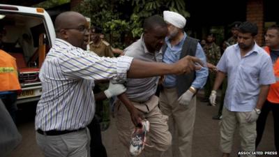 An injured person is helped on his arrival at the Aga Khan Hospital in Nairobi after an attack at the Westgate Mall