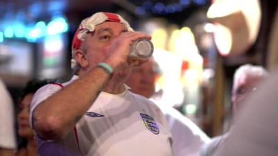 Man in an England shirt drinking beer