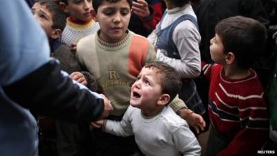 A Syrian child refugee cries as he stands at a queue waiting to receive aid from Turkish humanitarian agencies at Bab al-Salam refugee camp in Syria