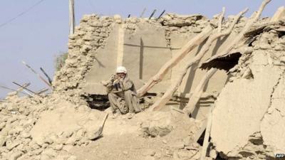 A survivor of Tuesday's earthquake sits on the ruins of his house in Pakistan's Awaran district.