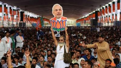 A supporter of the Bharatiya Janata Party holds an image of Narendra Modi.