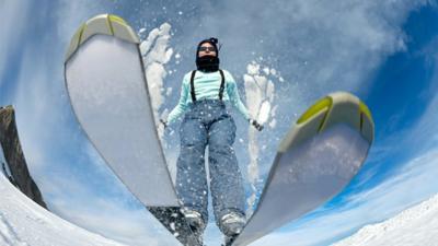 A skier jumps over a camera