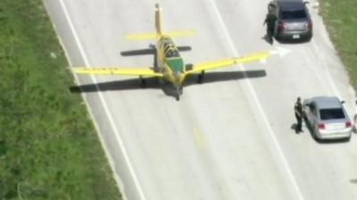 The plane taxis past cars on the road