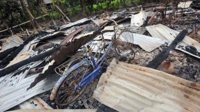 A bicycle stands in the ruins of a house