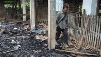Burma villager walks through torched building