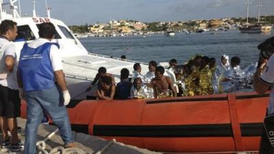 Rescued migrants arrive onboard a coastguard vessel at the harbour of Lampedusa