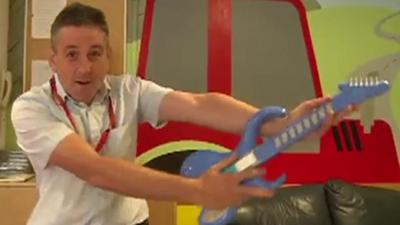 A member of hospital staff holding a toy guitar