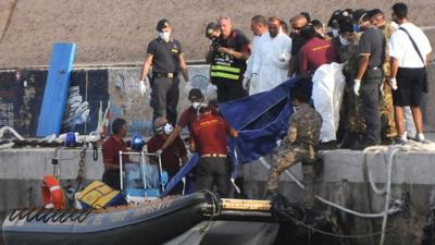 Rescuers lift a body bag as they reach the port of Lampedusa