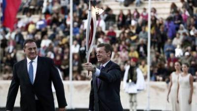 Russia"s Deputy Prime Minister Kozak raises an Olympic torch for the Sochi 2014 Winter Games next to President of the Greek Olympic Committee Kapralos