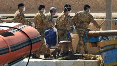 Italian military personnel disembark from a boat carrying the body of one of the African migrants killed in a shipwreck off the Italian coast in the harbour of Lampedusa