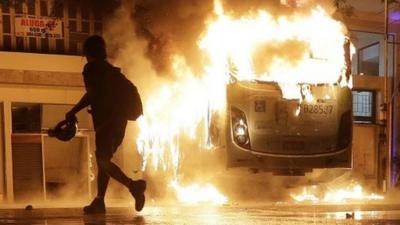 Man walks past a burning bus in Rio de Janeiro