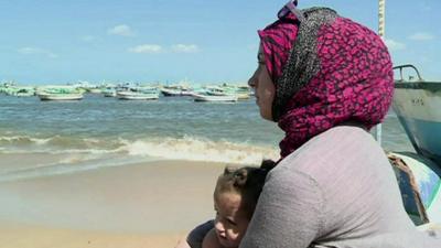 A Syrian refugee holds her daughter near the Alexandrian coast