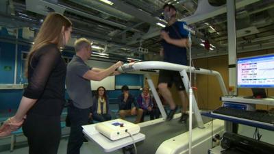 Man on a treadmill being monitored by health professionals