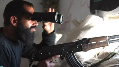 An opposition fighter uses binoculars to observe the movement of Syrian regime forces