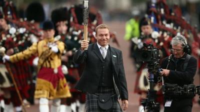 Sir Chris Hoy, Britain's most successful Olympian, carries the Queen's baton on the start of its journey around the Commonwealth countries ahead of the Glasgow 2014 Commonwealth Games.