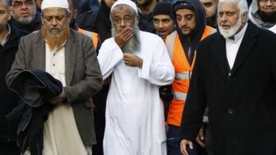 Sattar Taufiq walks with members of the community after funeral prayers for his wife and children at Spinney Hill Park in Leicester