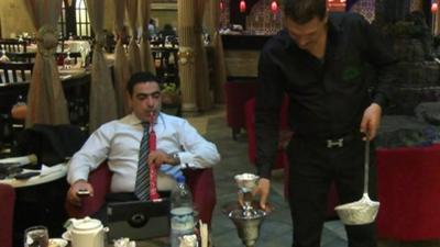 Man using laptop and smoking hookah pipe