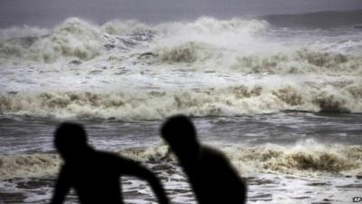 Two people run from huge waves on Gopalpur beach in Ganjam district