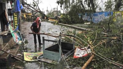 An man salvages a table stuck in uprooted trees which fell during Cyclone Phailin in Berhampur, India