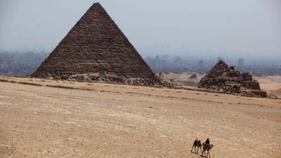 A man rides a camel past Khufu pyramid, the largest of pyramids at the historical site of the Giza Pyramids, near Cairo, Egypt