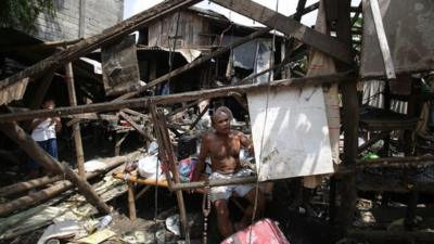 A Filipino resident sits inside his damaged house after Typhoon Nari hit San Miguel town