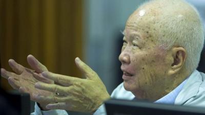 This handout photo taken and released by the Extraordinary Chamber in the Courts of Cambodia (ECCC) shows former Khmer Rouge leader head of state Khieu Samphan (C) talking to court officials in the courtroom