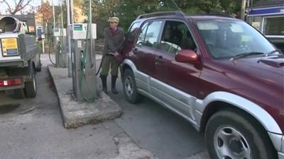 A man in a rural community filling his car with fuel