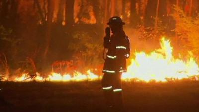 Firefighter with bushfires in the background