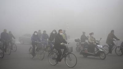 People ride along a street on a smoggy day in Daqing