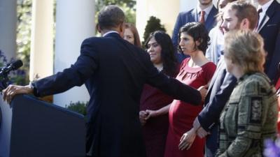 President Barack Obama reaches over to help an unidentified woman who started to lose her balance while he was speaking in the Rose Garden of the White House in Washington, Monday, on 21 October 2013