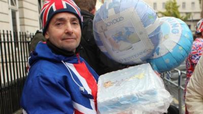 A man with christening balloons and a christening cake