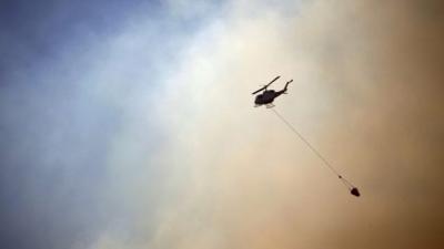 A helicopter drops water on a fire approaching homes near the Blue Mountains suburb of Blackheath