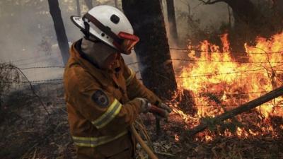 Fire fighter pours water on to flames.