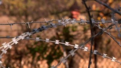 Man stands behind razor wire