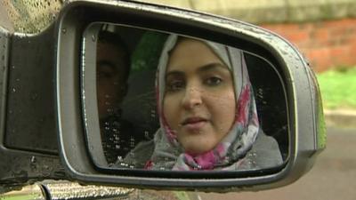 Women in reflection of car wing mirror