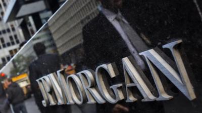 People walking past reflected in JP Morgan sign