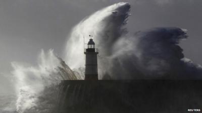 Waves crash against a lighthouse