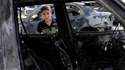 A boy inspects a destroyed car after a car bomb attack hit the Sha"ab neighbourhood of Baghdad