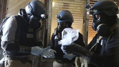 UN chemical weapons expert holds a plastic bag containing samples from one of the sites of an alleged chemical weapons attack in the Ain Tarma neighbourhood of Damascus in this August 29, 2013 file photo