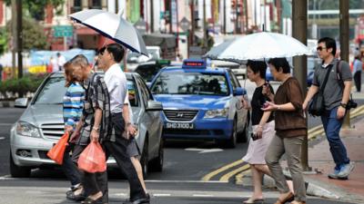 Pedestrians crossing in front of cars at a junction in Singapore