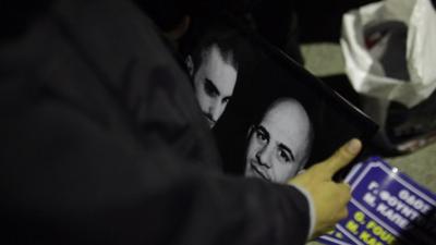 A supporter of the extreme right party of Golden Dawn, holds a picture with the images of Manolis Kapelonis, left, and Giorgos Foudoulakis, who were killed in a shooting