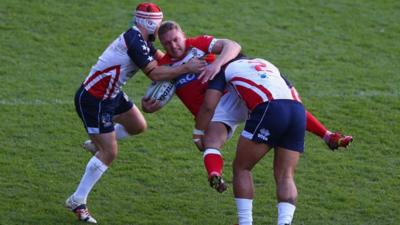 Christiaan Roets getting tackled by two USA players