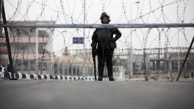 A riot policeman stands guard outside the complex where the trial will take place