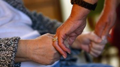 Carer holds patient's hand